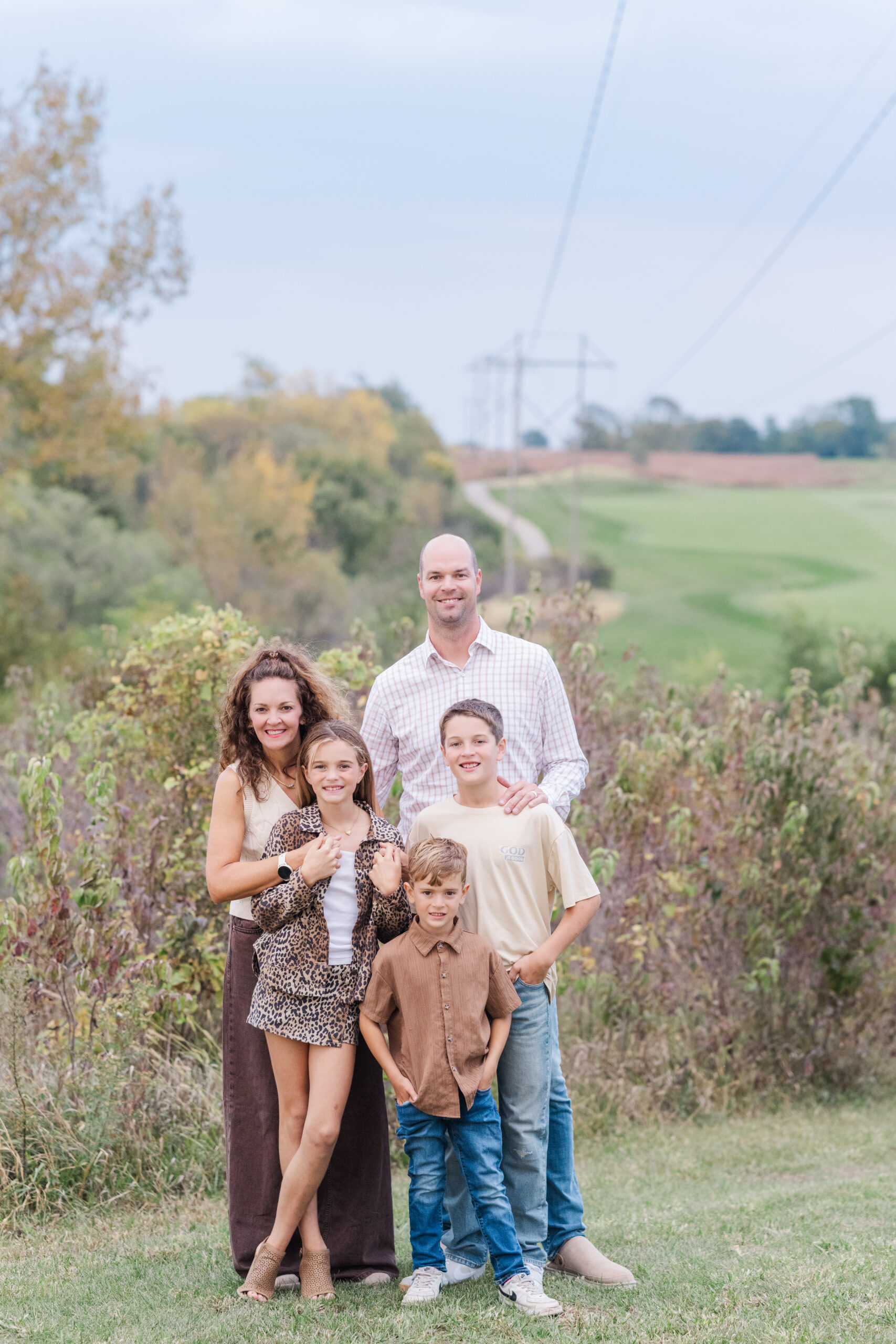 family of three children and two parents pose together on a golf course