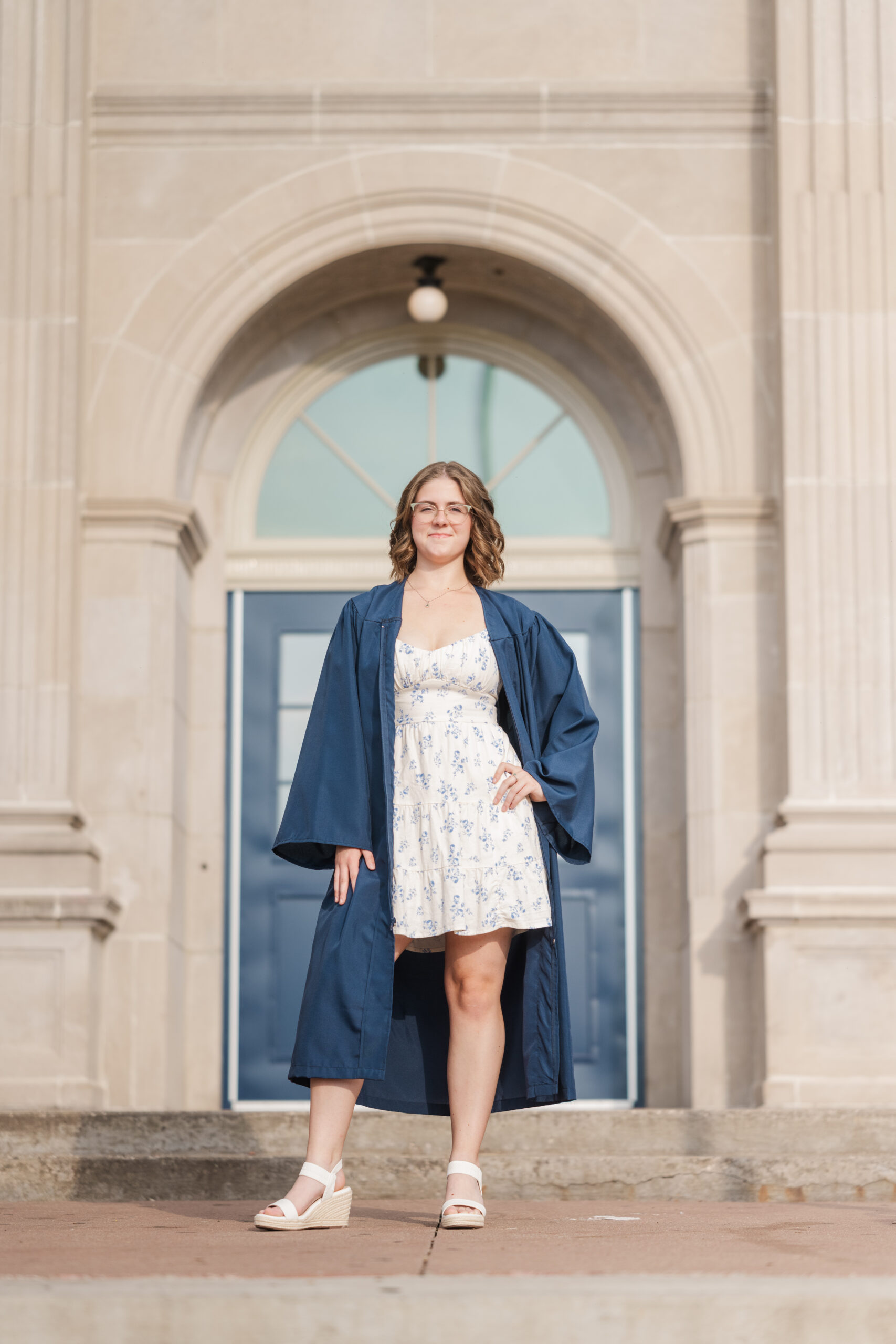 high school senior standing in graduation gown in front of school